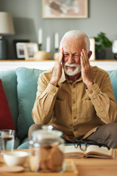 一位老人坐在客厅的沙发上患了偏头痛图片下载