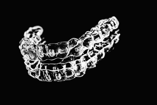 看不见的牙齿矫正器牙齿固定器躺在镜子上的黑白照片图片下载