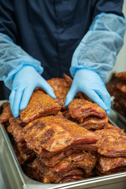在生产现场，手拿着烤炉里的烤猪排。野餐或乡间别墅的美味小吃概念图片下载