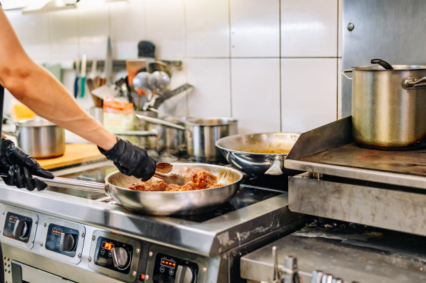 女厨师在厨房用酱汁煮鸡翅图片下载