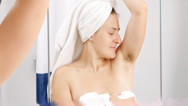 年轻女子在浴室里闻着自己腋下长出的汗毛。卫生、自然美、女性和体毛生长的概念。图片下载