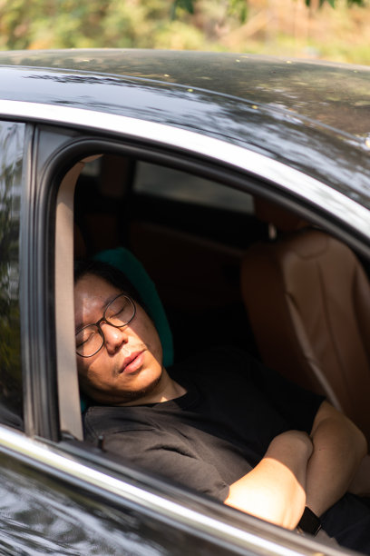 亚洲大块头男子在车里等朋友的时候睡着了，所以他双臂交叉坐在驾驶座上。图片下载