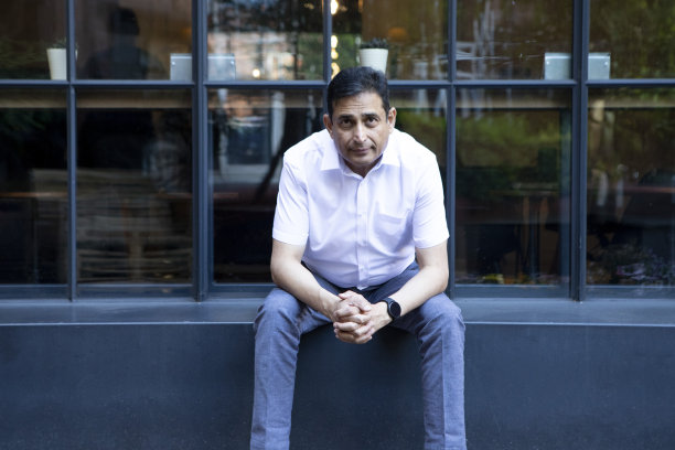 一位成熟的商人坐在一栋现代建筑外图片下载