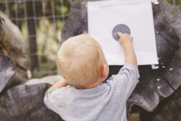 蹒跚学步的小女孩在森林里检查目标板图片下载