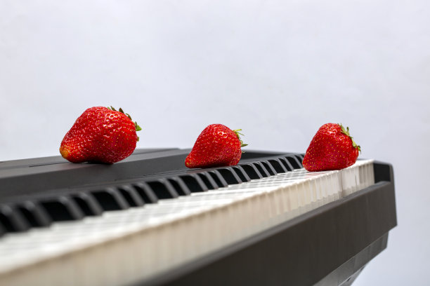 三个成熟的草莓在钢琴琴键上图片下载