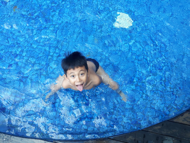 空中高角度拍摄的男孩在游泳池里玩耍的照片。暑假是学校给孩子放假的日子图片下载