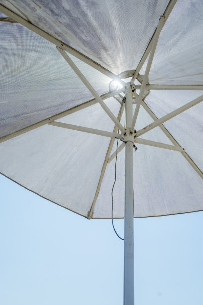 白色的遮阳伞映衬着深蓝色的天空，暗示着佛罗里达炎热的夏日。图片下载