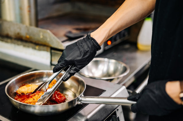 女厨师在厨房用酱汁煮鸡翅图片下载