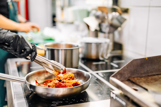 女厨师在厨房用酱汁煮鸡翅图片下载