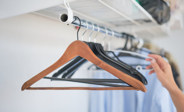 女人的手从衣架上取下衬衫，一个空荡荡的衣橱。有选择性的重点图片下载