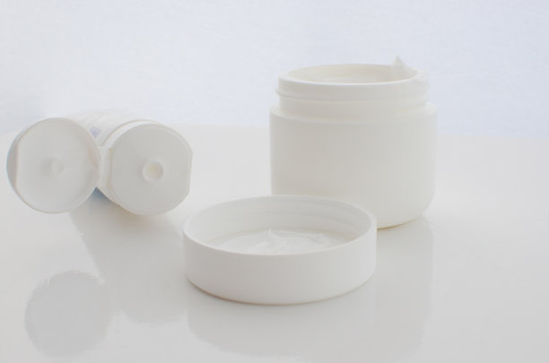 一罐白色面霜的特写，象征着美学护理和容光焕发的皮肤。图片下载