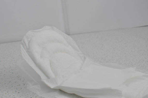 一张白色卫生巾放在桌子上的极简主义照片，象征女性气质和个人护理。图片下载