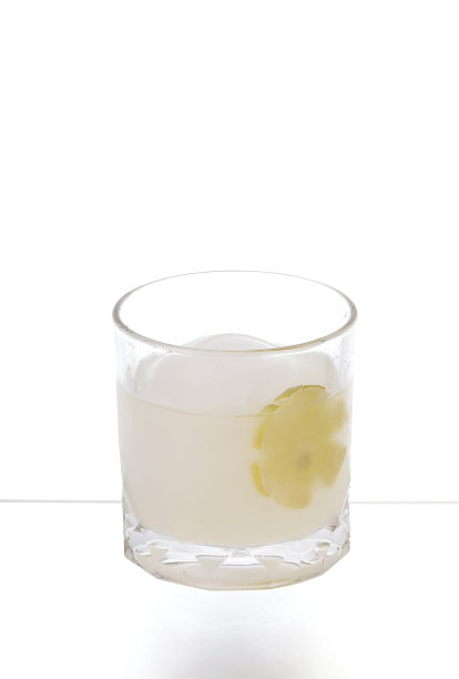 鸡尾酒和冰球(圆形)装在玻璃杯里，白色背景上有柠檬片。图片下载