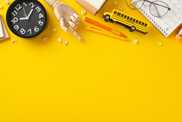 返校的设置。人体模型手俯视图，在生动的黄色背景上显示各种学校用品，如字母，笔，眼镜，时钟，日历，玩具巴士，并留出文字或广告空间图片下载