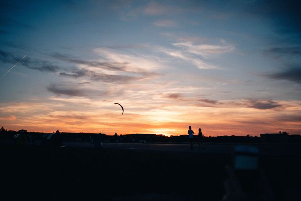 日落时分，慢跑者跑过柏林的Tempelhofer费尔德。夏天的剪影。图片下载