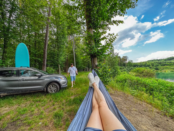 一名女子躺在越野车旁边的吊床上图片下载