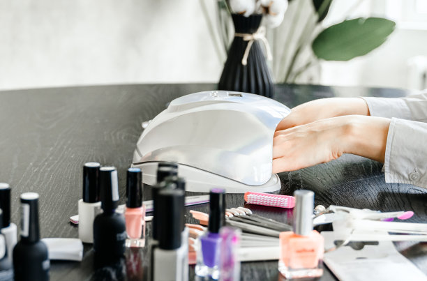 美容院的专业美甲师。修甲服务，手部护理，指甲，手指护理。多色指甲油，样品调色板，纹身，角质层油，凝胶紫外线灯，手套图片下载