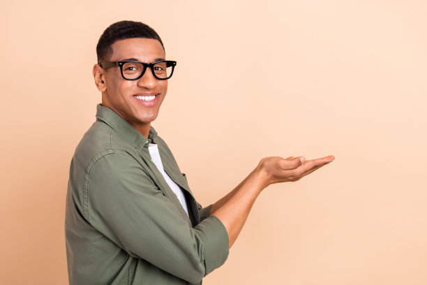 照片正面的好心情的家伙穿着卡其布衬衫，显示手臂空白空间孤立米色背景图片下载