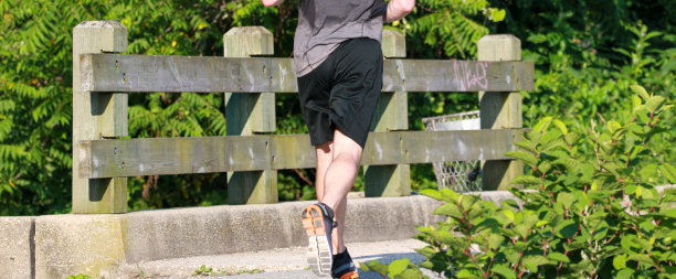 在一个炎热的夏天早晨，一个人跑过树林里的一座小桥图片下载