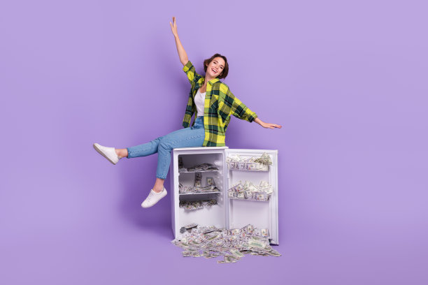 年轻时髦女子的全身照片玩坐在冰箱很多钱飞翅膀手臂无忧无虑孤立在紫罗兰色的背景图片下载