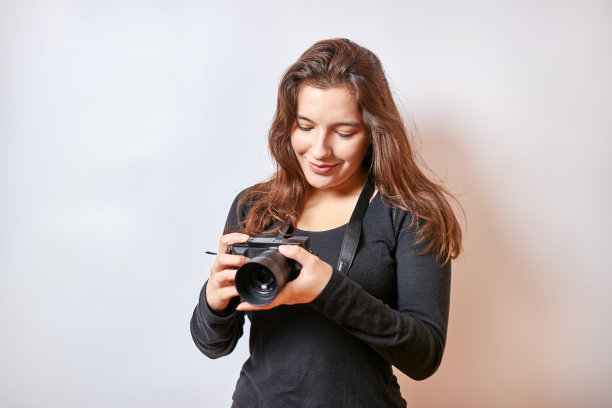 漂亮的女孩看着数码相机拍摄的照片。图片下载