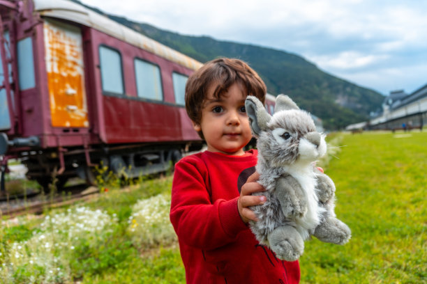 一个孩子带着毛绒玩具在比利牛斯山脉的坎弗朗火车站玩耍。西班牙图片下载