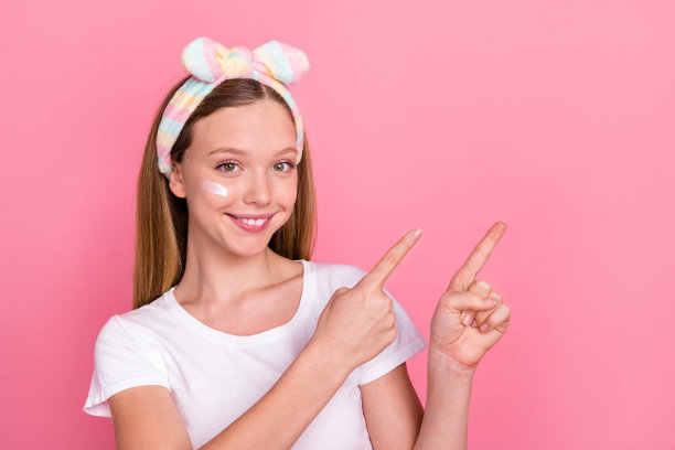 可爱的甜美少女的肖像，手指空着，穿着白色t恤，孤立在粉红色的背景上图片下载