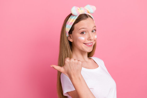 迷人少女的个人资料照片显示手指空白的面霜，在粉红色的背景下孤立的眼睛图片下载