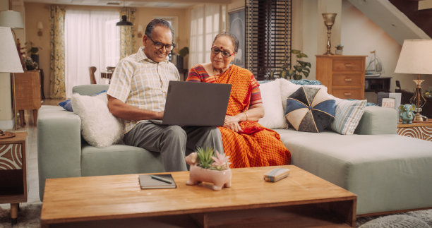 老年夫妇在家中使用笔记本电脑:从搜索旅游目的地到分享难忘的照片，共同从事在线活动。快乐的老夫妇积极享受退休生活。媒介图片下载