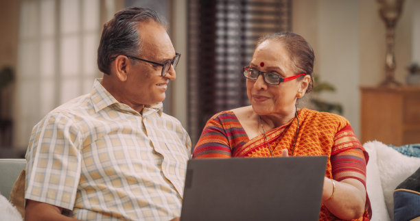 美丽的印度老夫妇在家里使用笔记本电脑:浏览网站的服装，产品销售，选择最好的网上购物。微笑快乐的奶奶和爷爷喜欢花时间在一起图片下载