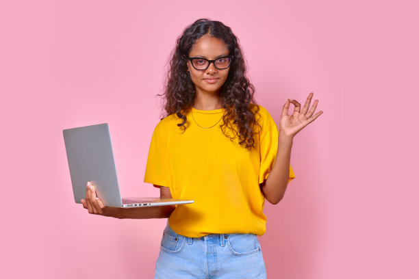 年轻可爱的印度少女拿着打开的笔记本电脑，做着OK的手势图片下载