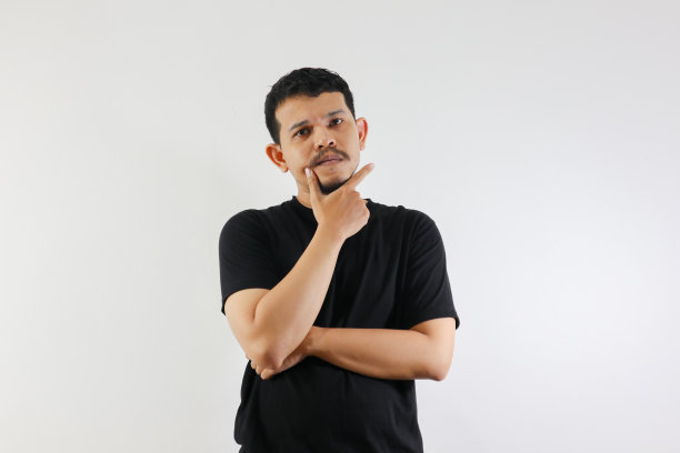 穿着黑色休闲衬衫的成年亚洲男子，露出沉思的姿态，疑惑的表情图片下载