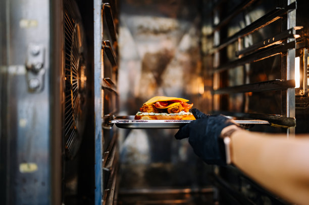 厨师在餐厅厨房的烤箱里手工烹饪奶酪汉堡图片下载