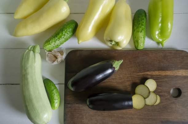 白色的桌子上放着炖菜用的茄子、甜椒、大蒜和黄瓜。准备新鲜的夏季蔬菜炖菜。图片下载