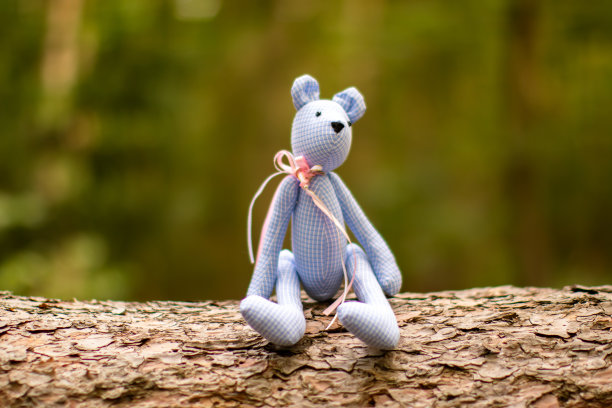 玩具熊坐在森林里的树干上图片下载