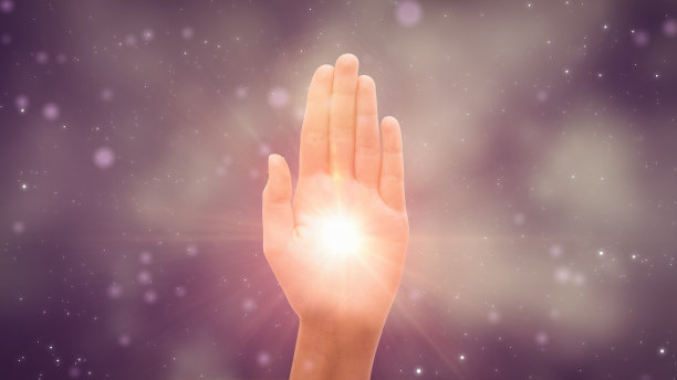 在深紫色背景上，男性或女性伸出手展示Hamsa宗教手势的可视化。明亮的光在棕榈中央发光。传统保护标志概念。图片下载
