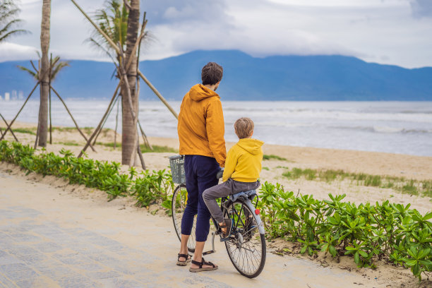 一个夏日，父亲带着儿子在美丽的风景中骑着自行车周末出游图片下载
