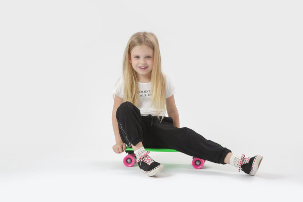 漂亮的金发小女孩的工作室肖像与滑板图片下载