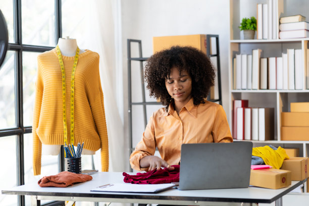 非裔美国女孩在网上直播展示和销售服装。美丽微笑的女顾客在网上购物时选择时尚的衣服，图片下载