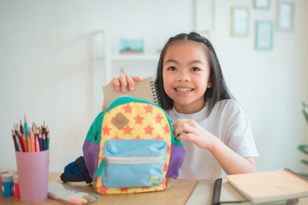 小学生把书和笔记放进书包里。学习用品。回到学校的概念。孩子们准备学习。肖像可爱的小女孩打包背包。图片下载