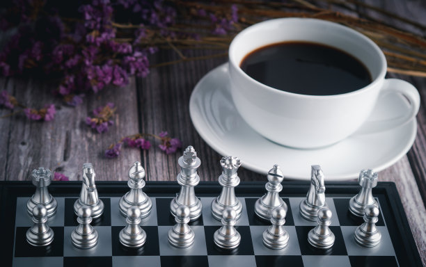 棋盘上的国际象棋游戏的正面视图与白色咖啡杯模糊的背景。商业游戏竞争策略。商业战略的概念。图片下载