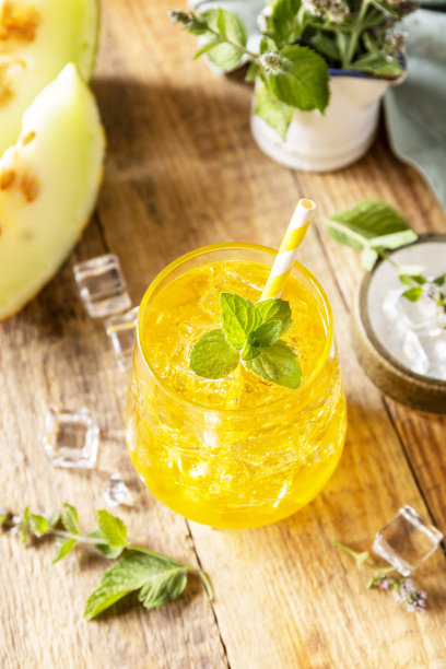 在质朴的木桌上，一杯柠檬甜瓜汁，加冰块和薄荷。清新爽口的夏季果香饮料，时令饮料。图片下载