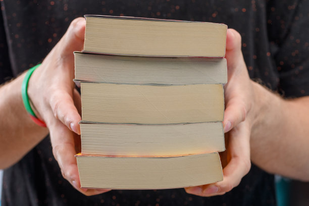 一个学生手里拿着一堆从图书馆借来的书图片下载