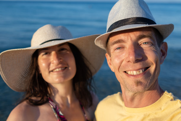 幸福的家庭夫妇站在沙滩上自拍。图片下载