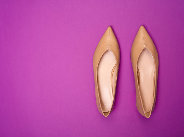 优雅的米色尖头女鞋的俯视图，前面有针脚装饰，脚趾在明亮的紫色背景上与复制空间隔离。鞋子大甩卖，清仓广告概念。图片下载