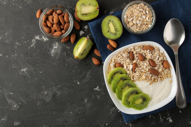 希腊白酸奶配猕猴桃杏仁和燕麦片放在深色石墨桌子上。早餐。前视图。健康的食物图片下载
