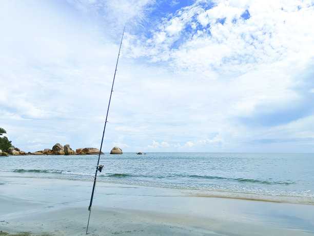 海滩上的鱼竿选择性聚焦，蓝色的大海和蓝天为背景图片下载
