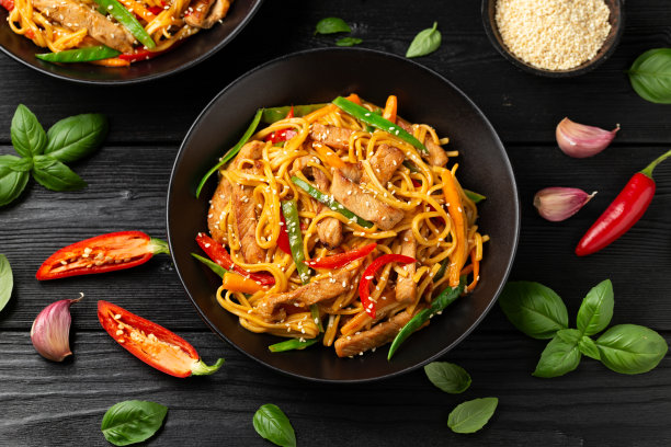 用黑碗翻炒猪肉蔬菜炒面。亚洲风味食品图片下载