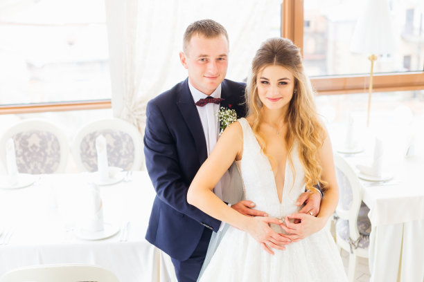 新郎身穿西装，系着领结，挽着新娘的腰图片下载