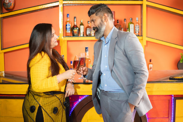 快乐的印度商人手里拿着葡萄酒和香槟，男女公司聚会庆祝公司成功。图片下载